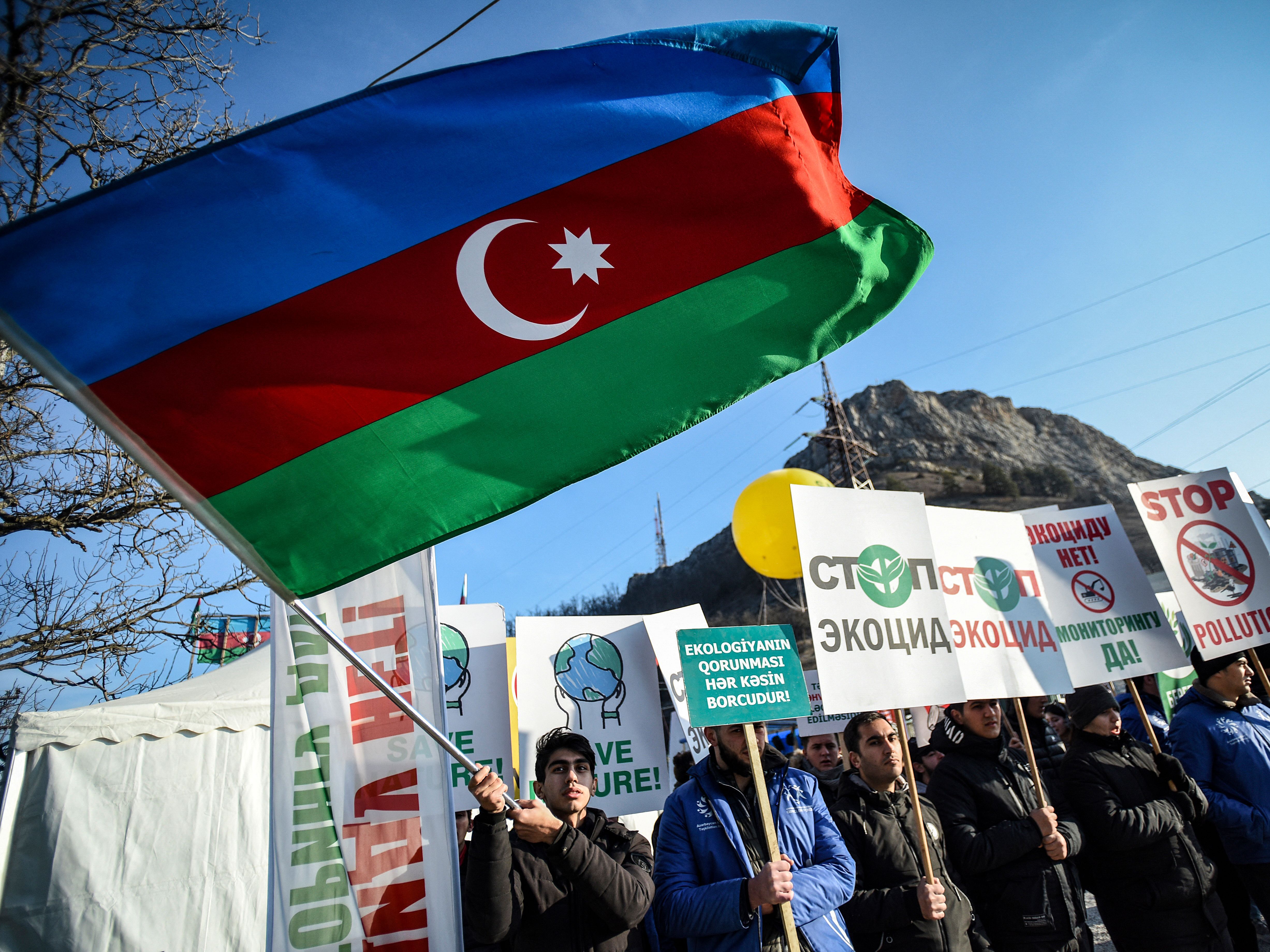 caption: An Azerbaijani environmental activist waves a national flag during a protest against what they claim is illegal mining at the Lachin corridor, the only land link between the Armenian-populated breakaway Nagorno-Karabakh region and Armenia.