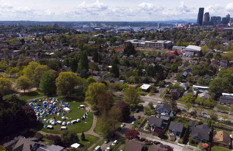 caption: An aerial view of Powell Barnett Park shows several tents set up by unsheltered migrants after losing their temporary shelter on Wednesday, May 1, 2024, in Seattle. 