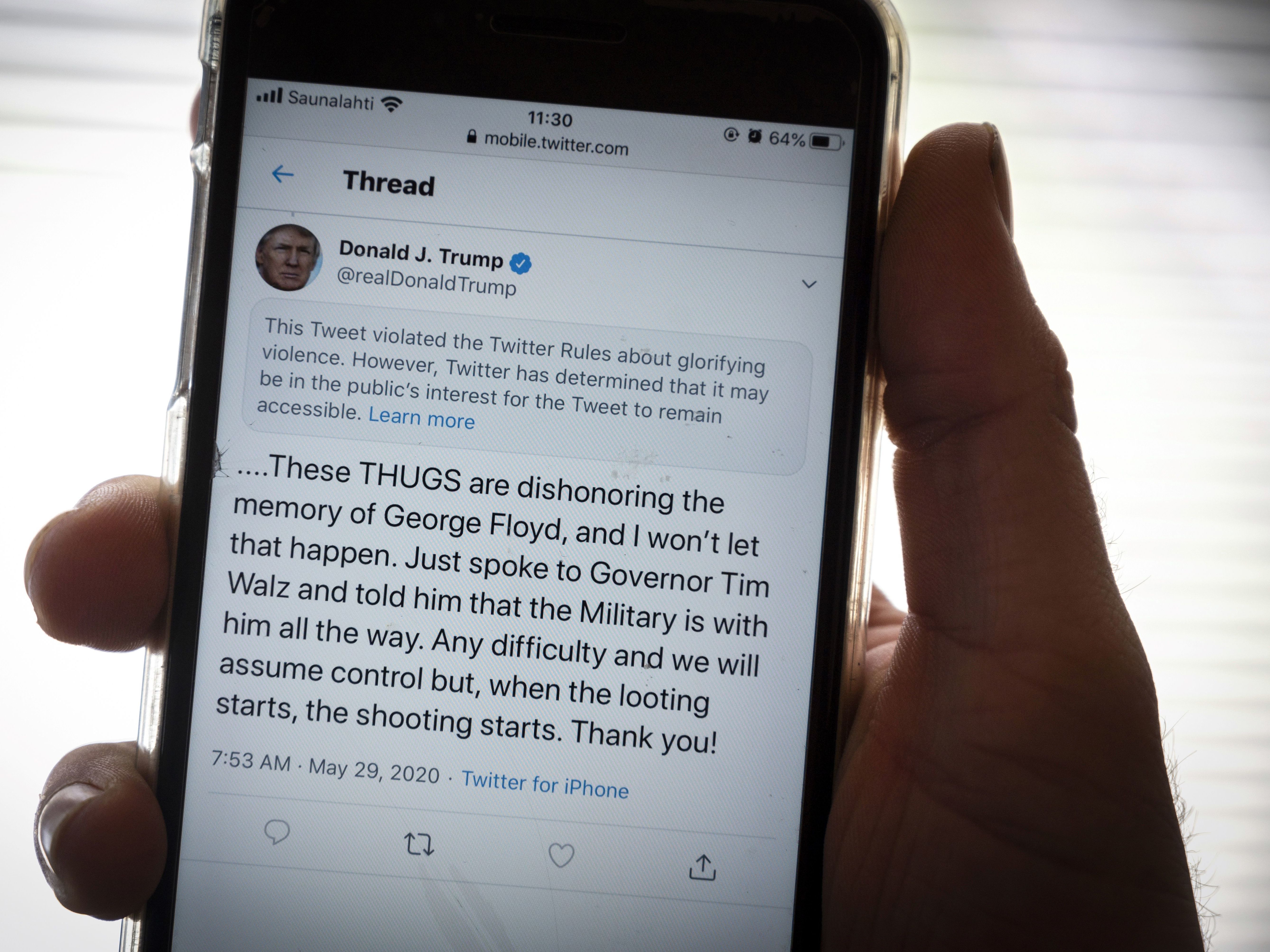 caption: President Trump's Twitter page is displayed on a mobile phone. The social media company flagged one of his tweets about Minneapolis as "glorifying violence" and hid it from public view unless a user clicks on it.
