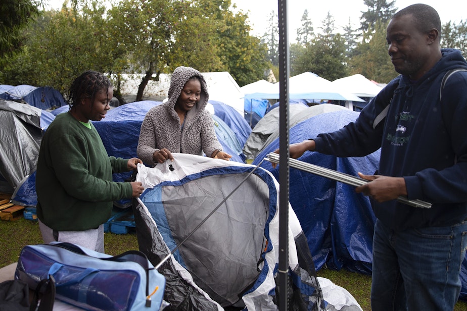 caption: From left, Juliana Mateus, Isabel Ndumba Domingos, and Francois Makaya, of Angola, work to set up a tent outside of the Riverton Park United Methodist Church, where nearly 200 people are sheltering while seeking asylum, on Monday, Oct. 16, 2023, in Tukwila.