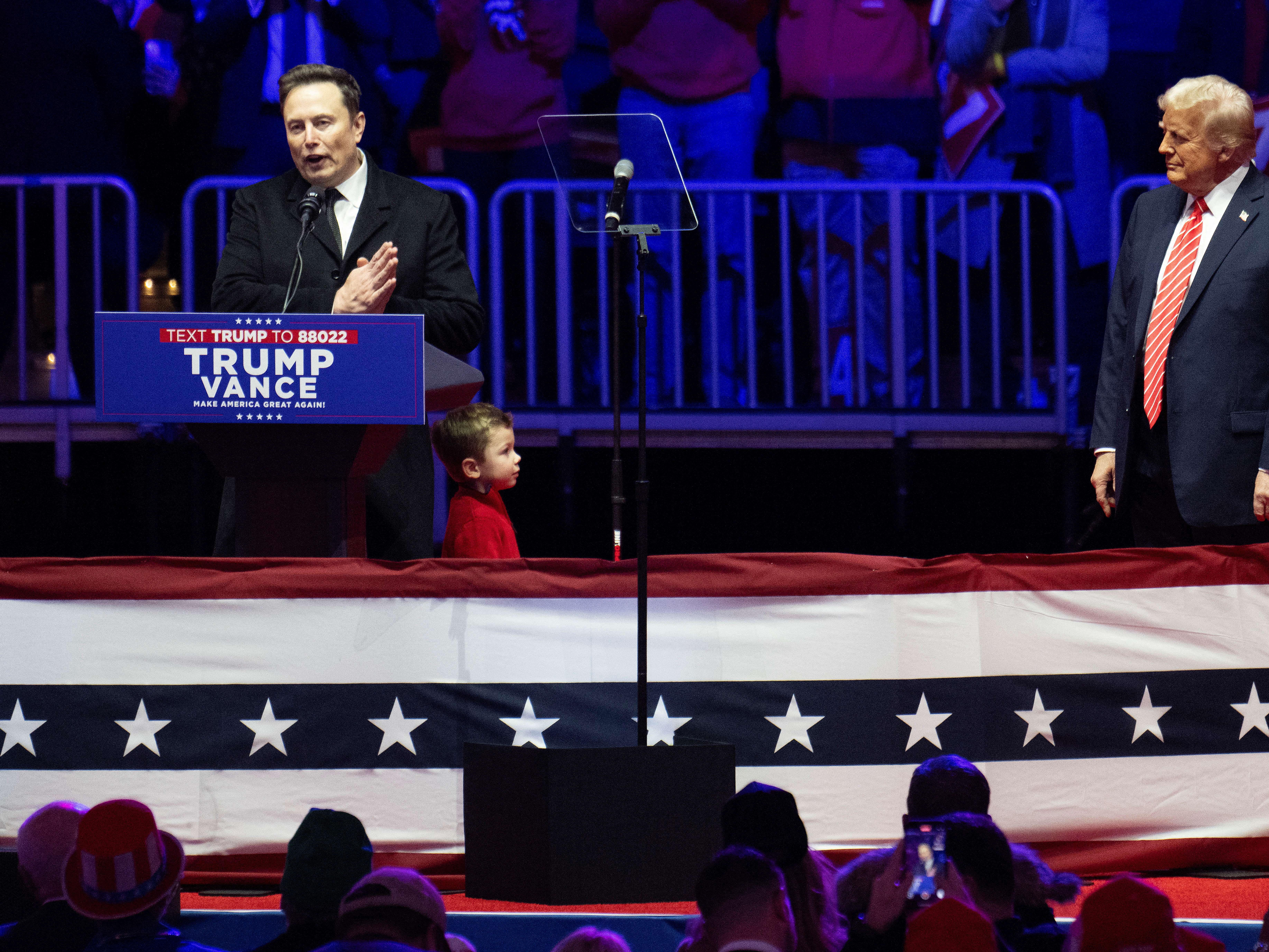 caption: Billionaire Elon Musk (left) is seen as the architect of the "deferred resignation" offer to federal employees. He sent a similarly worded offer to Twitter staff when he bought that company in 2022. Here, he speaks as President Trump looks on at a MAGA victory rally on Jan. 19.