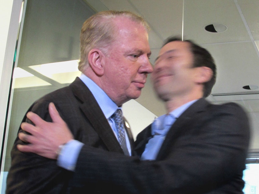 caption: Mayor Ed Murray, left, on Friday afternoon after denying accusations of rape. His husband gave him a quick embrace as he left the podium.
