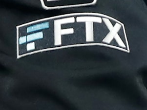 caption: The FTX logo appears on home plate umpire Jansen Visconti's jacket at a baseball game with the Minnesota Twins on Sept. 27, 2022, in Minneapolis.