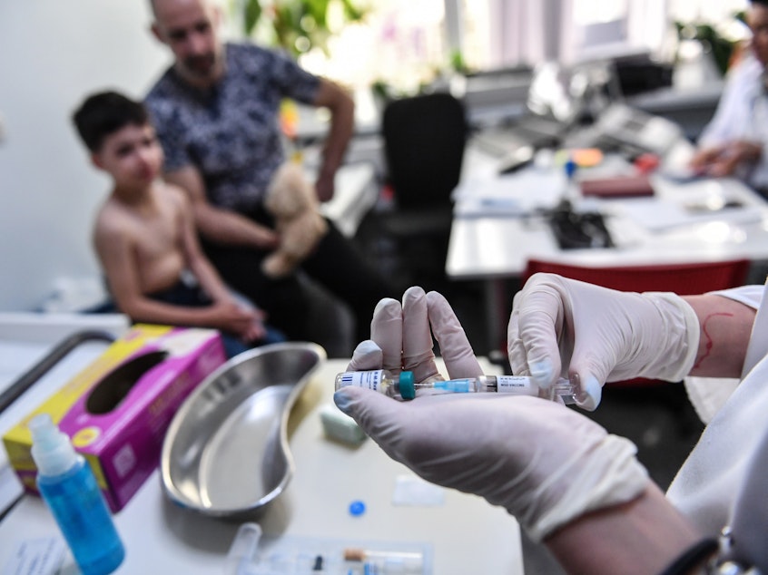caption: Measles cases have spiked globally after years of decline. Here, a family physician prepares a measles vaccine in Bucharest, Romania. Doctors there say that parental hesitancy about vaccines and lack of faith in state institutions have hurt immunization efforts.