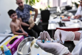 caption: Measles cases have spiked globally after years of decline. Here, a family physician prepares a measles vaccine in Bucharest, Romania. Doctors there say that parental hesitancy about vaccines and lack of faith in state institutions have hurt immunization efforts.