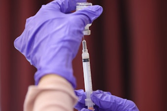 caption: A nurse draw a Moderna COVID-19 vaccine dose from a vial at the Cameron Grove Community Center in Bowie, Md., in late March. Moderna says study data supports use of a half-dose of the vaccine in children 6 to 11.
