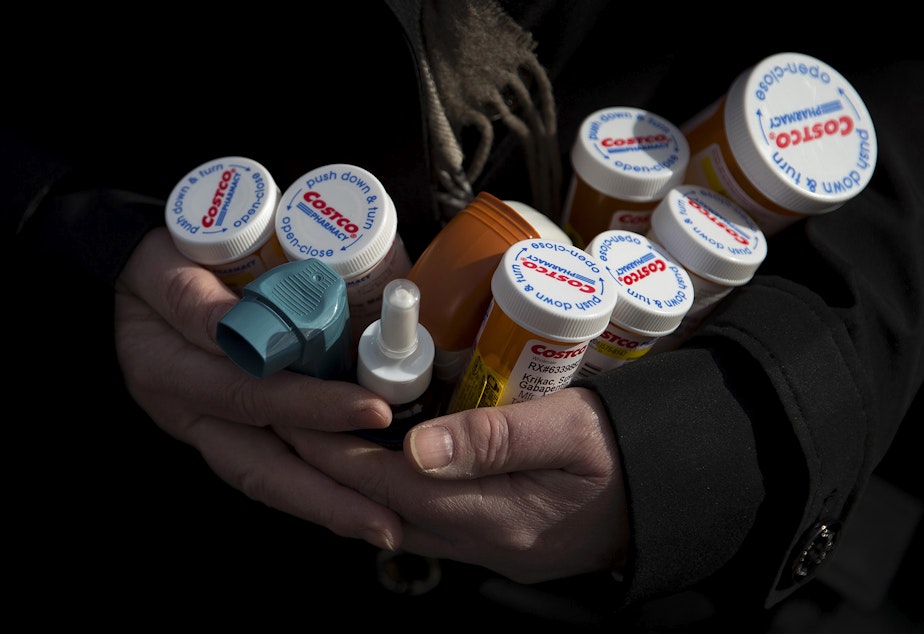 caption: Susan Krikac holds a small fraction of the medications that she was prescribed while she was positive with Covid-19 at her home on Wednesday, February 17, 2021, in Seattle. After testing positive in July, she is still experiencing various symptoms of Covid-19 today, seven months later, requiring an entirely different set of medications. 