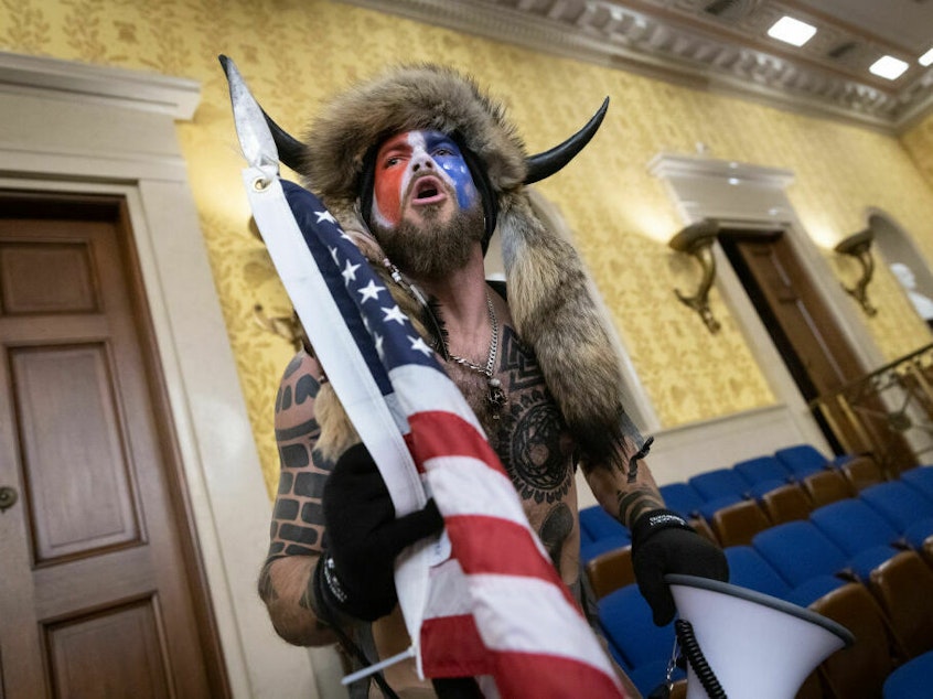 caption: Jacob Chansley, also known as the "QAnon Shaman," screams "freedom" inside the U.S. Senate chamber after the U.S. Capitol was breached by a mob during a joint session of Congress on January 6, 2021, in Washington, D.C.