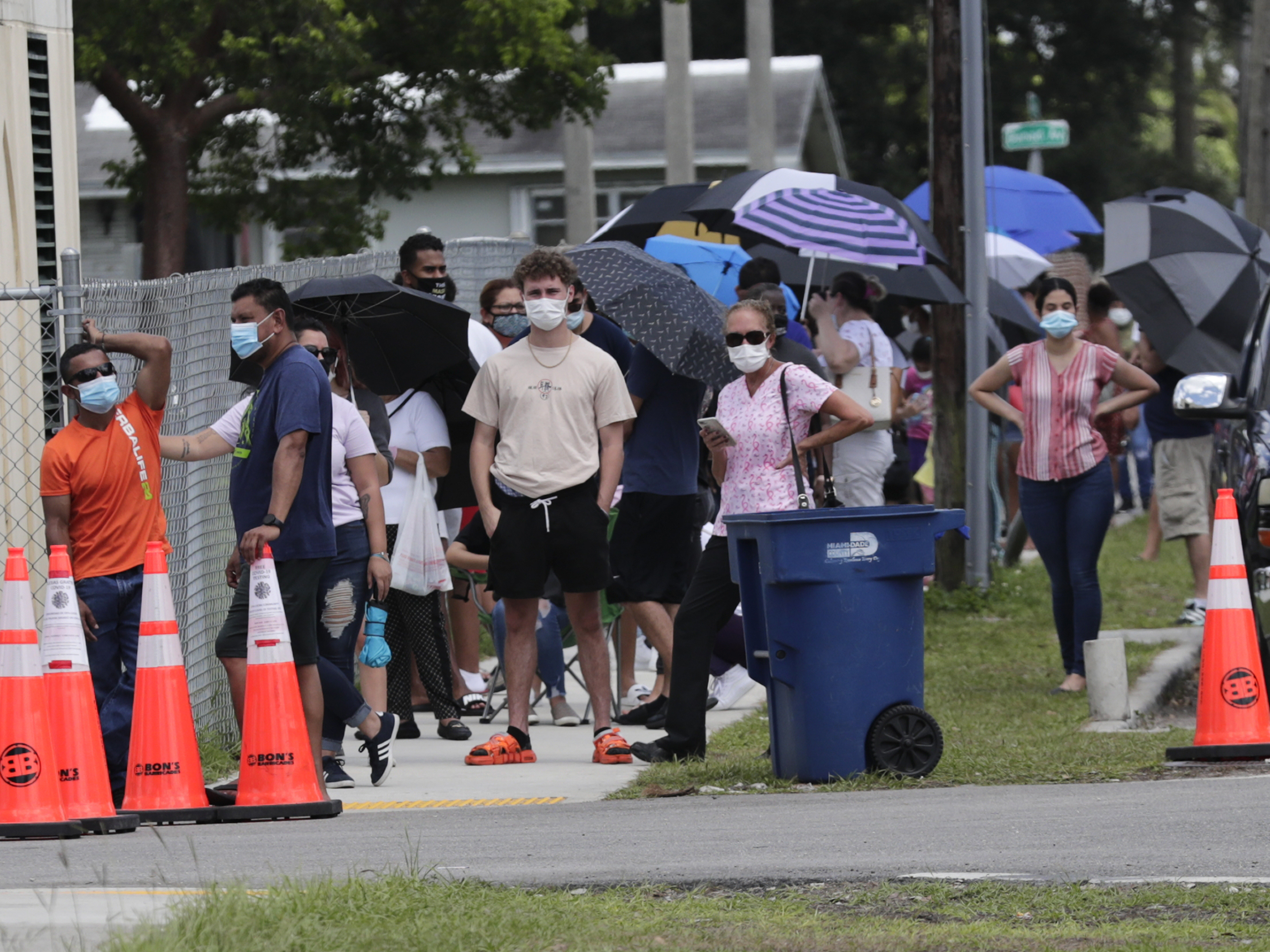 caption: People wait in line outside of a COVID-19 testing site in Florida. The state has seen unprecedented surges in coronavirus cases in recent weeks.