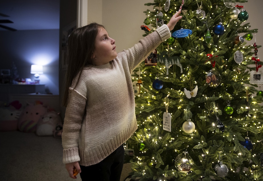 caption: Caileigh Mrsny, 7, points to a favorite ornament on a Christmas tree dedicated to her father, Kurt Mrsny, on Thursday, December 9, 2022, at their home in Puyallup. 