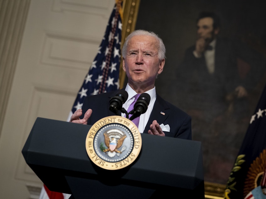 caption: President Biden speaks about the coronavirus pandemic in the State Dining Room of the White House on Tuesday.