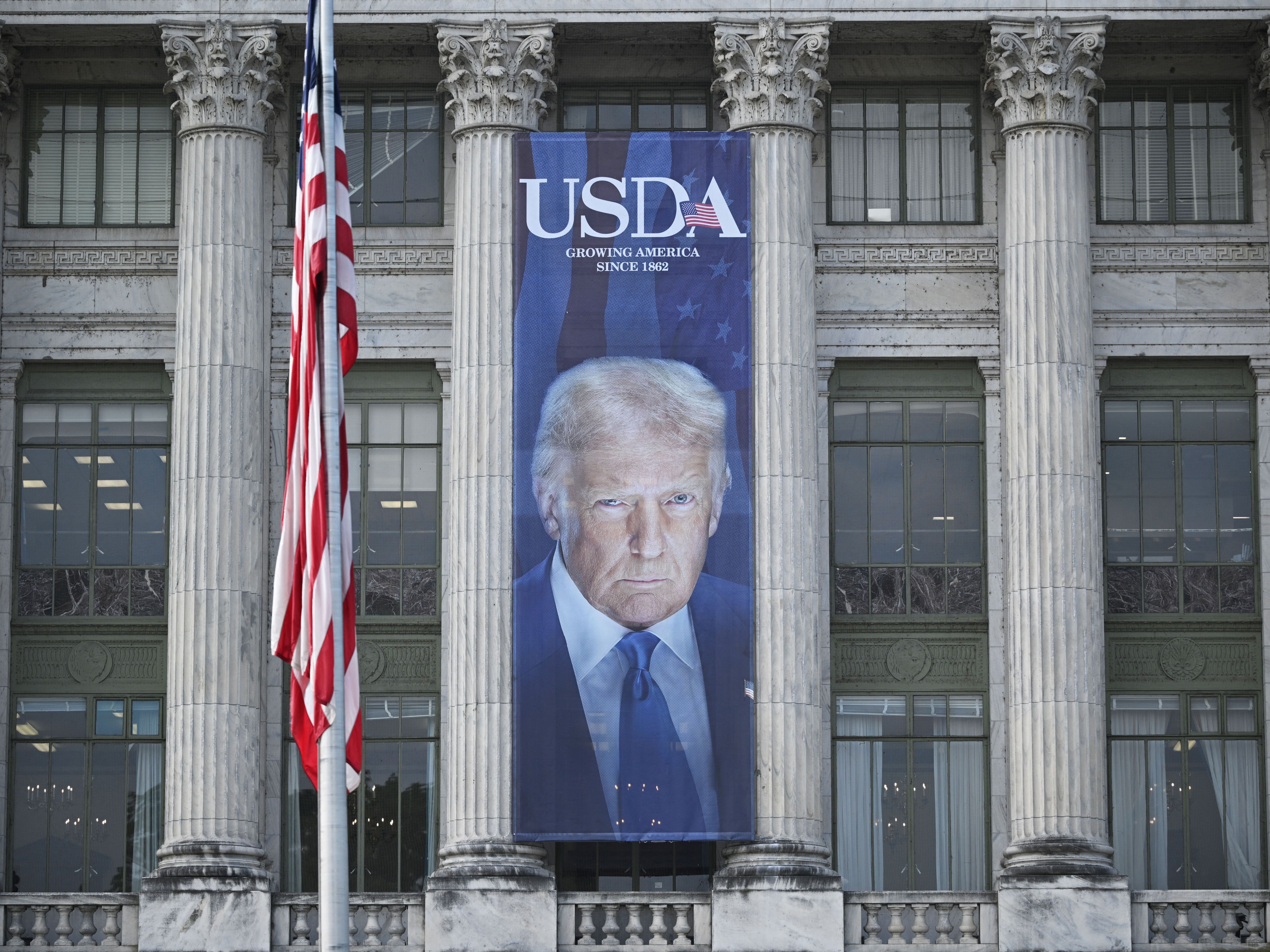 caption: A banner showing an image of President Trump hangs on the side of the U.S. Department of Agriculture building in Washington, DC. The department wants states to turn over records about tens of millions of people who have received federally-funded nutrition assistance by July 30.