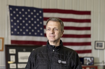 caption: Dr. Todd Rasmussen stands in his home office in Rochester, Minn. He is a former combat surgeon who did six tours in Iraq and Afghanistan.