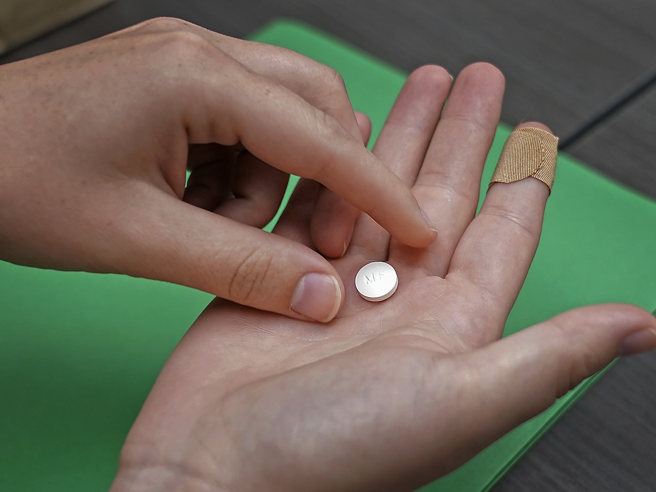 caption: A patient prepares to take the first of two combination pills, mifepristone, for a medication abortion during a visit to a clinic in Kansas City, Kan. in 2022.