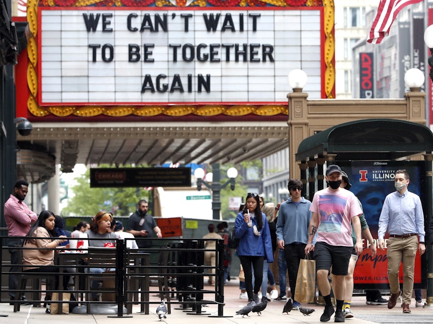 caption: People walk near the Chicago Theatre on Tuesday in the city's Loop community. The Centers for Disease Control and Prevention eased its guidelines on the wearing of masks, saying fully vaccinated Americans don't need to cover their faces anymore in most settings. Will it encourage the unvaccinated to get their shots?