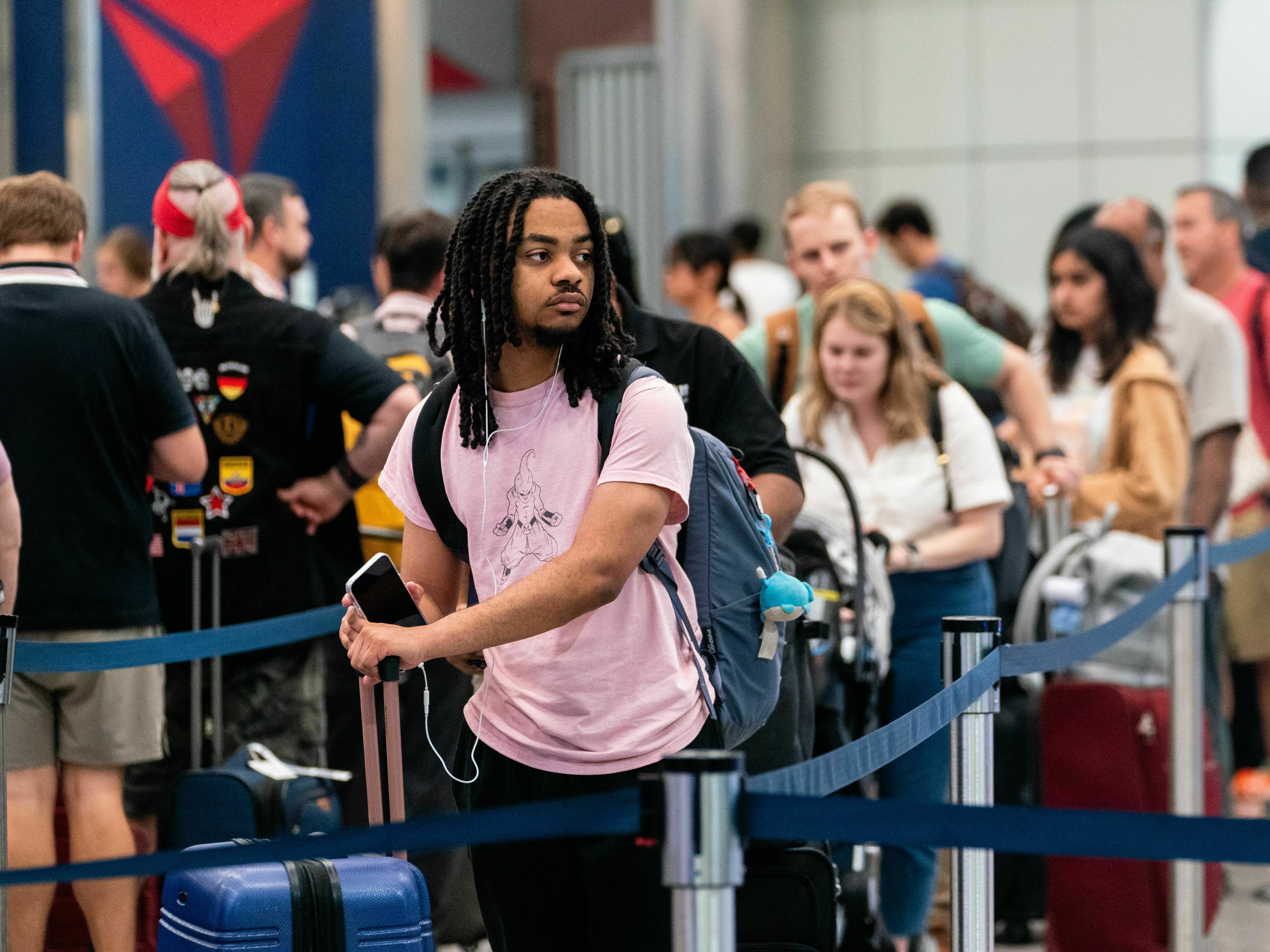 caption: Travelers wait in line at Hartsfield-Jackson Atlanta International Airport in Atlanta on June 30, 2023, ahead of the 4th of July holiday weekend.  Consumers are traveling and eating out more though they are paring down spending in other ways.