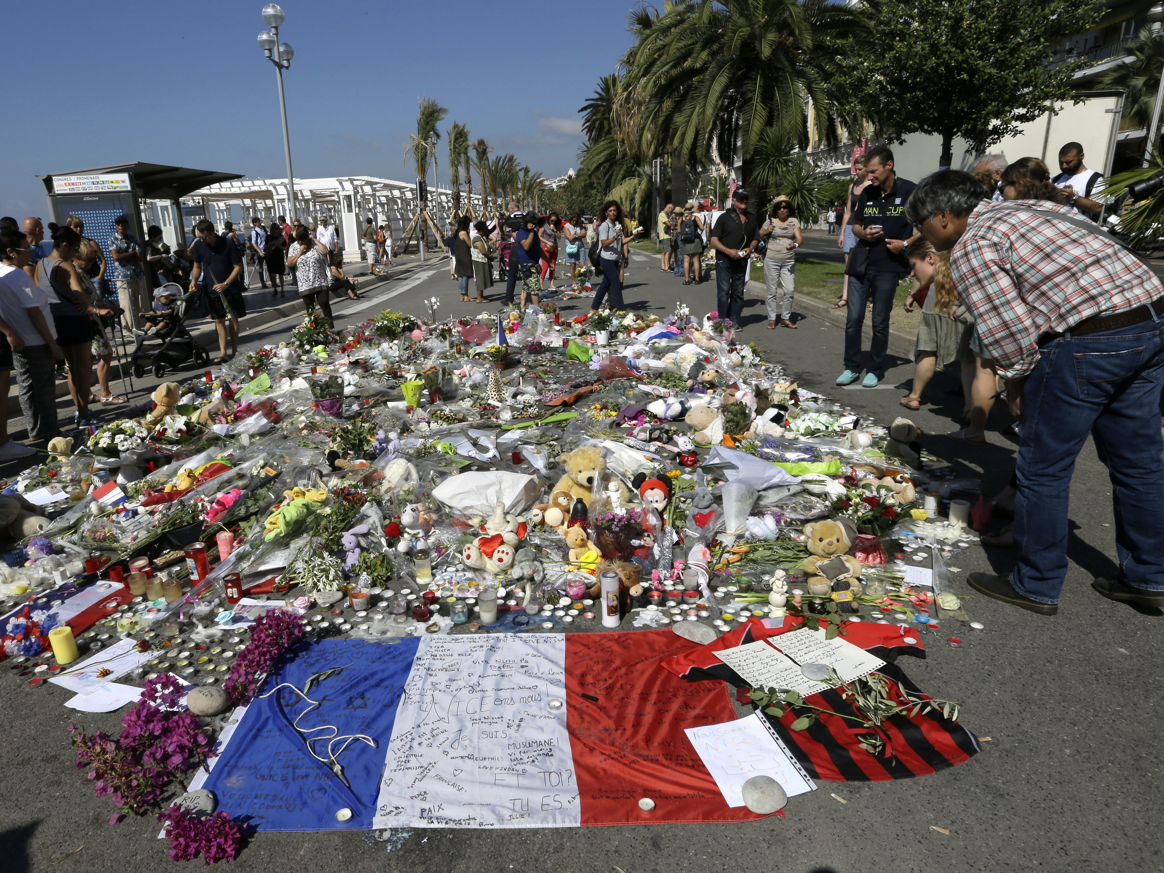caption: People look at flowers placed on the Promenade des Anglais at the scene of a truck attack on July 18, 2016, in Nice, southern France. A French court on Tuesday convicted eight people charged in connection with the Bastille Day attack that killed 86 people.