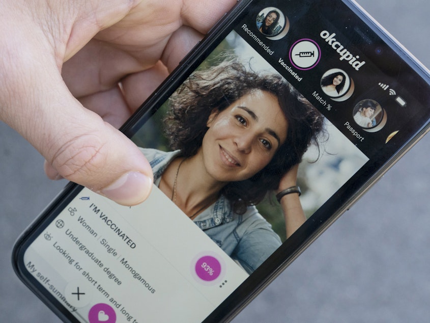 caption: A sample page on the OkCupid app is held for a photograph showing the "I'm vaccinated," checkmark, Friday, May 21, 2021, in Washington.