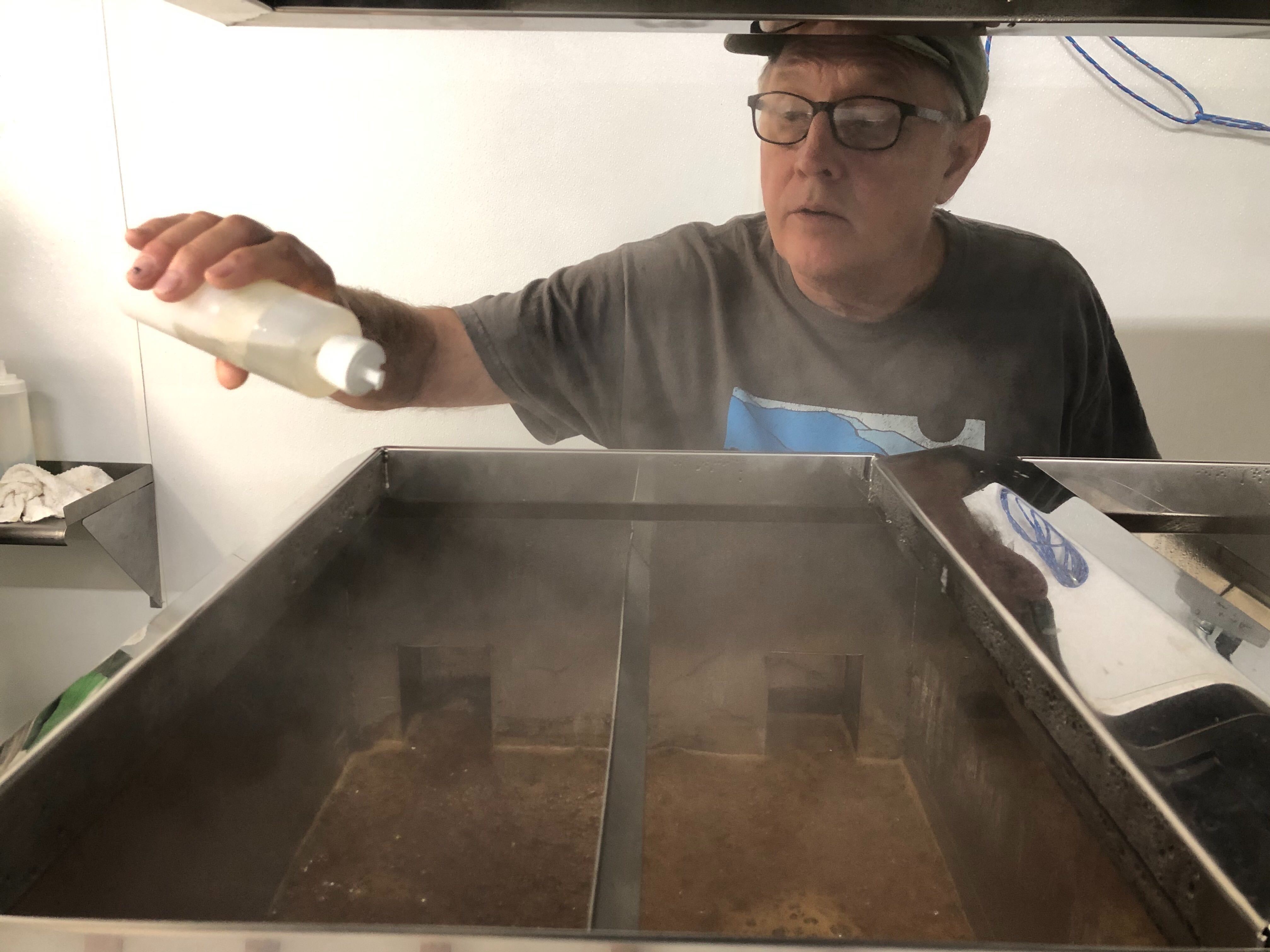 caption: Neil McLeod, owner of Neil's Bigleaf Maple Syrup farm, keeps a close eye on his reducing sap for out of control foaming.