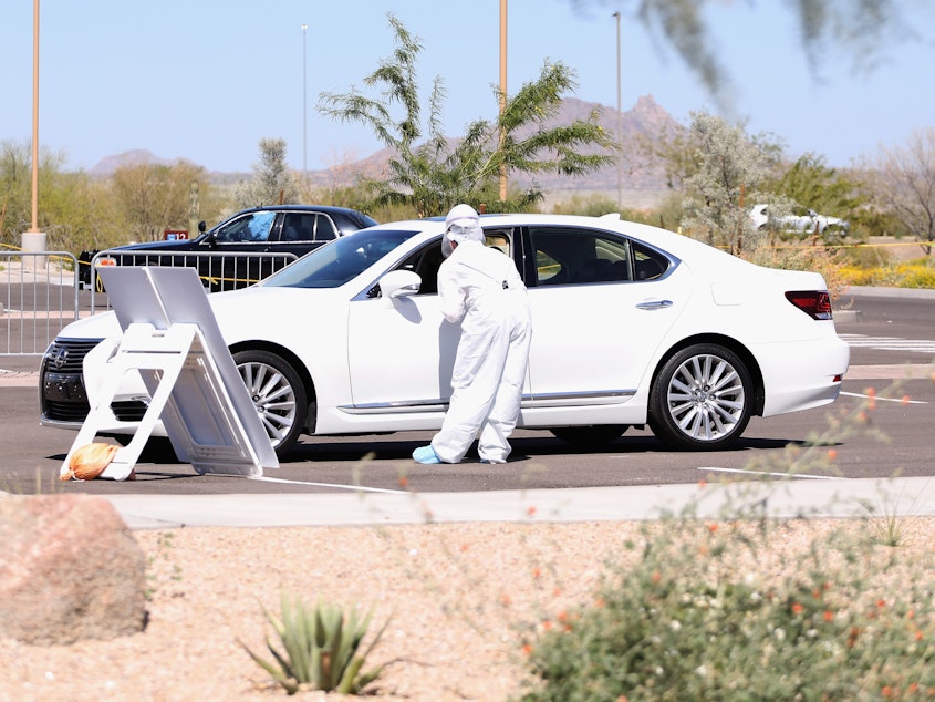 caption: Health care professionals prepare to screen people for the coronavirus at a testing site in Phoenix, Arizona.