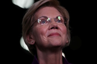 caption: Sen. Elizabeth Warren, D-Mass., speaks to the media in the spin room after the first night of the Democratic presidential debate in Miami last month.