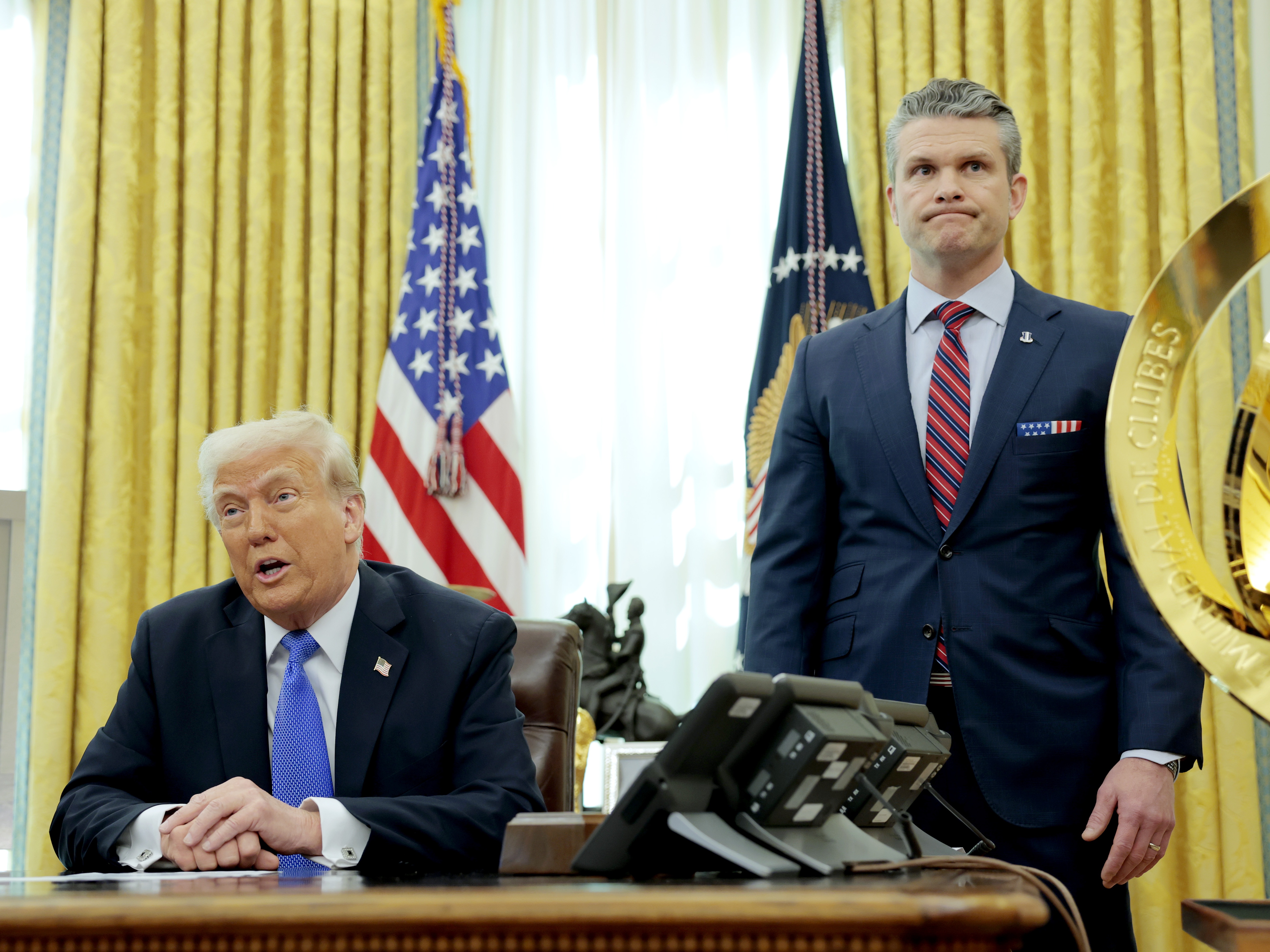 caption: President Trump speaks alongside Secretary of Defense Pete Hegseth in the Oval Office on March 21. Days earlier, Hegseth shared details about overseas war plans in a group chat on Signal, an encrypted, open-source messaging app, according to <em>The Atlantic</em>.
