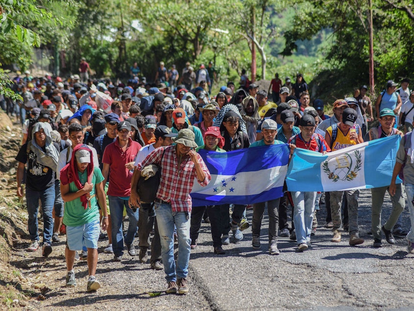 caption: Migrants heading toward the U.S. carry Honduran and Guatemalan national flags in Guatemala on Monday. President Trump has threatened to cut off aid to Honduras, Guatemala and El Salvador for failing to stop the caravan's journey.