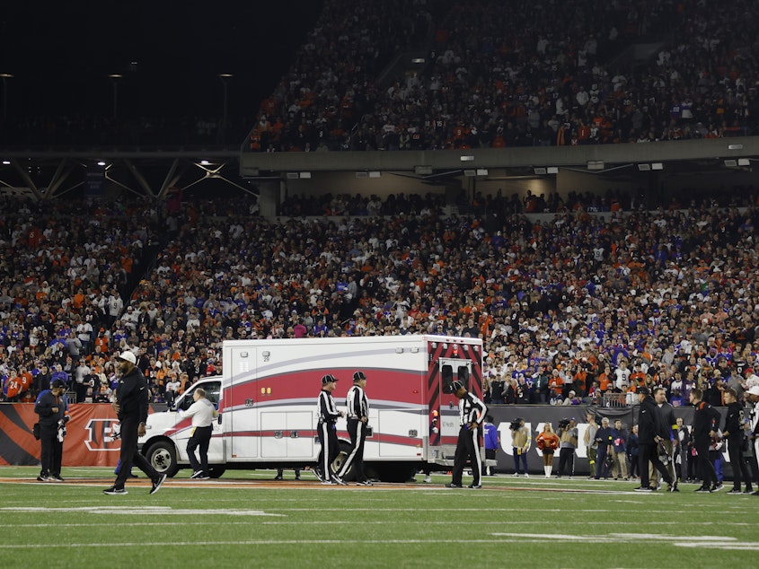 caption: Fans watch as Buffalo Bills football player Damar Hamlin leaves Cincinnati's Paycor Stadium in an ambulance on Monday night after experiencing a cardiac arrest during a game.