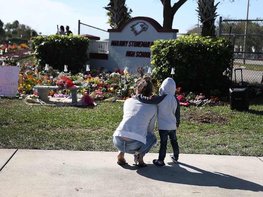 caption: A memorial is seen outside Marjory Stoneman Douglas High School in Parkland, Fla., in honor of those killed during a 2018 mass shooting. Families of more than a dozen victims have reached a legal settlement with the Justice Department.