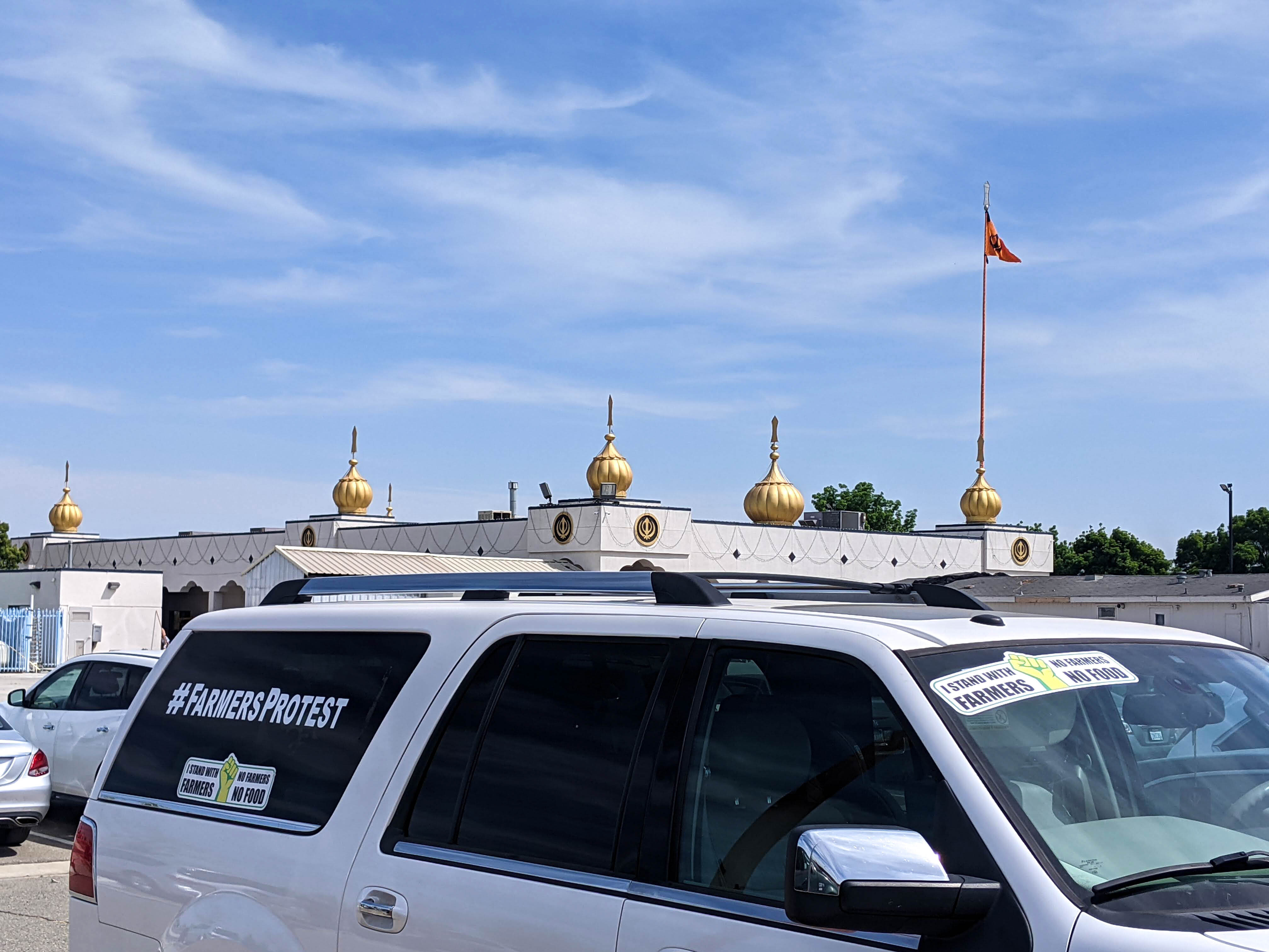 caption: A car parked in a Fresno Gurdwara, or Sikh temple, parking lot with a bumper sticker showing support for Indian farmers protesting new agricultural laws.
