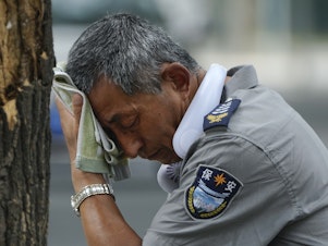 caption: A security guard wipes sweat from his brow in Beijing, on July 3, 2023. Record-breaking heat is unfolding around the world because of human-caused climate change and the cyclic climate pattern El Niño.