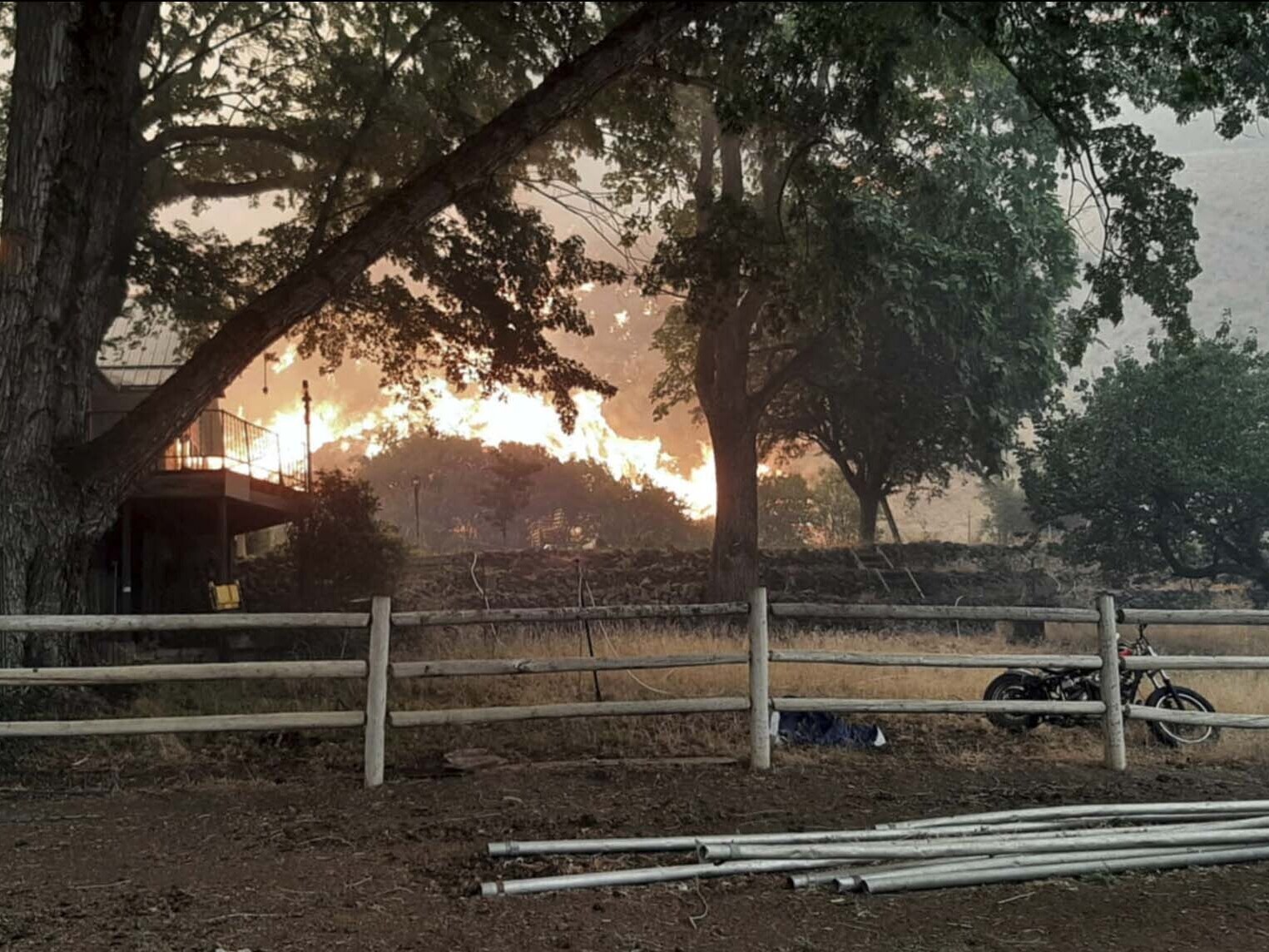 caption: A fast-moving wildfire near the Oregon-Idaho border moves toward a home on Rye Valley Lane in Huntington, Ore., on Wednesday afternoon.