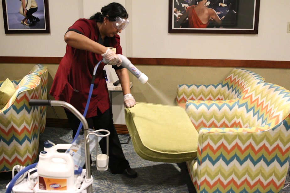 caption: Prem Chandra demonstrates how she sprays down furniture with an atomized disinfectant using the Clorox 360 machine. 