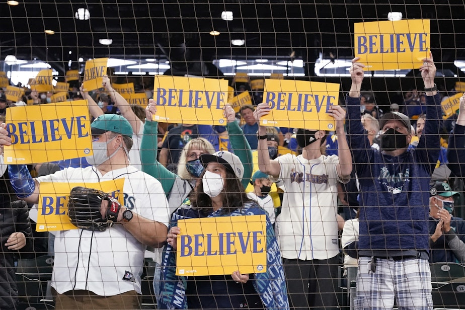 caption: Seattle Mariners' fans wave "Believe" signs before a baseball game against the Los Angeles Angels Sunday, Oct. 3, 2021, in Seattle. The slogan made known from the television show "Ted Lasso" has been adopted by the team in their battle to make it to the playoffs for the first time in two decades. 