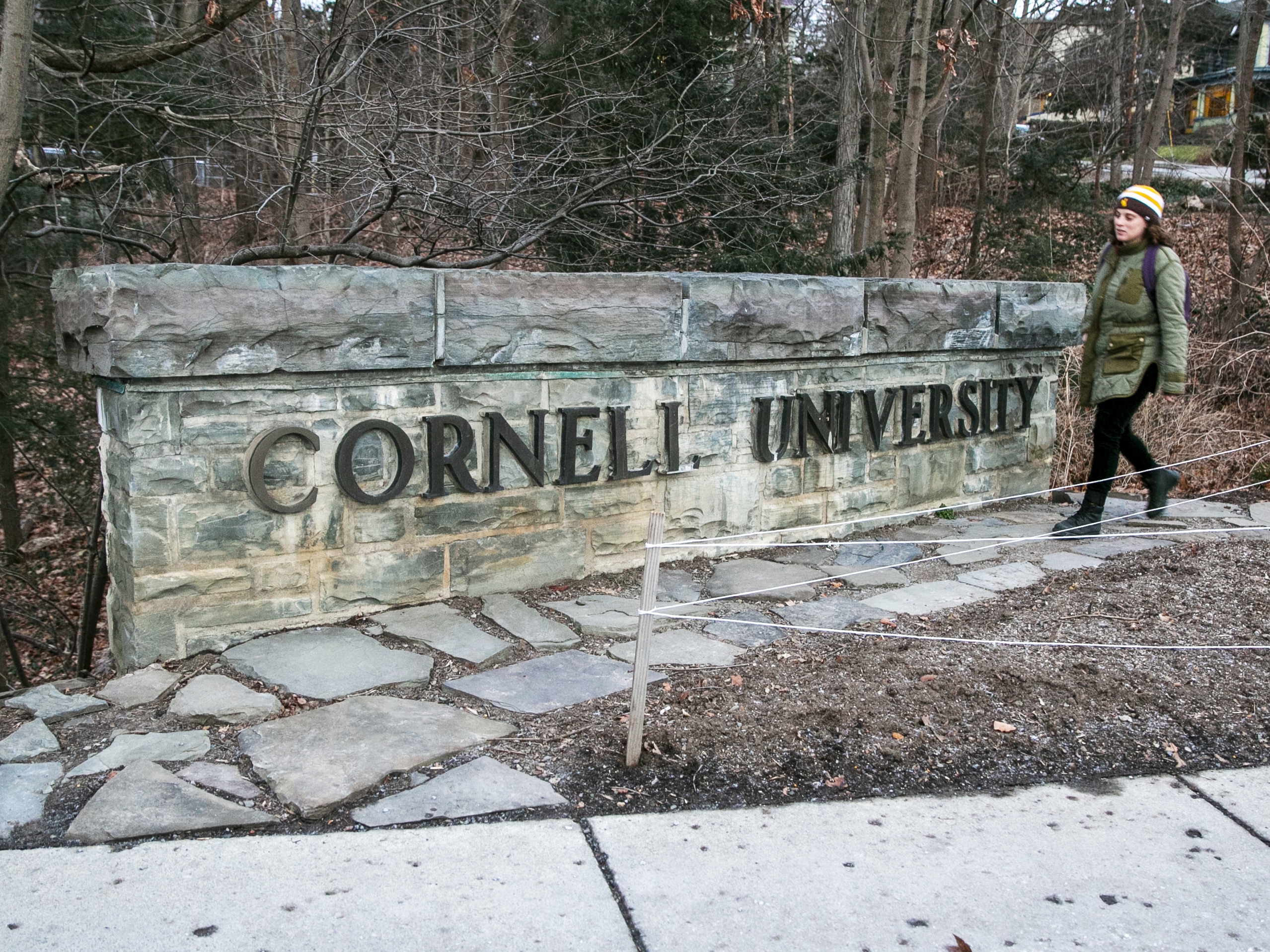 caption: A woman walks by a Cornell University sign on the Ivy League school's campus in Ithaca, New York, on Friday, Jan. 14, 2022.