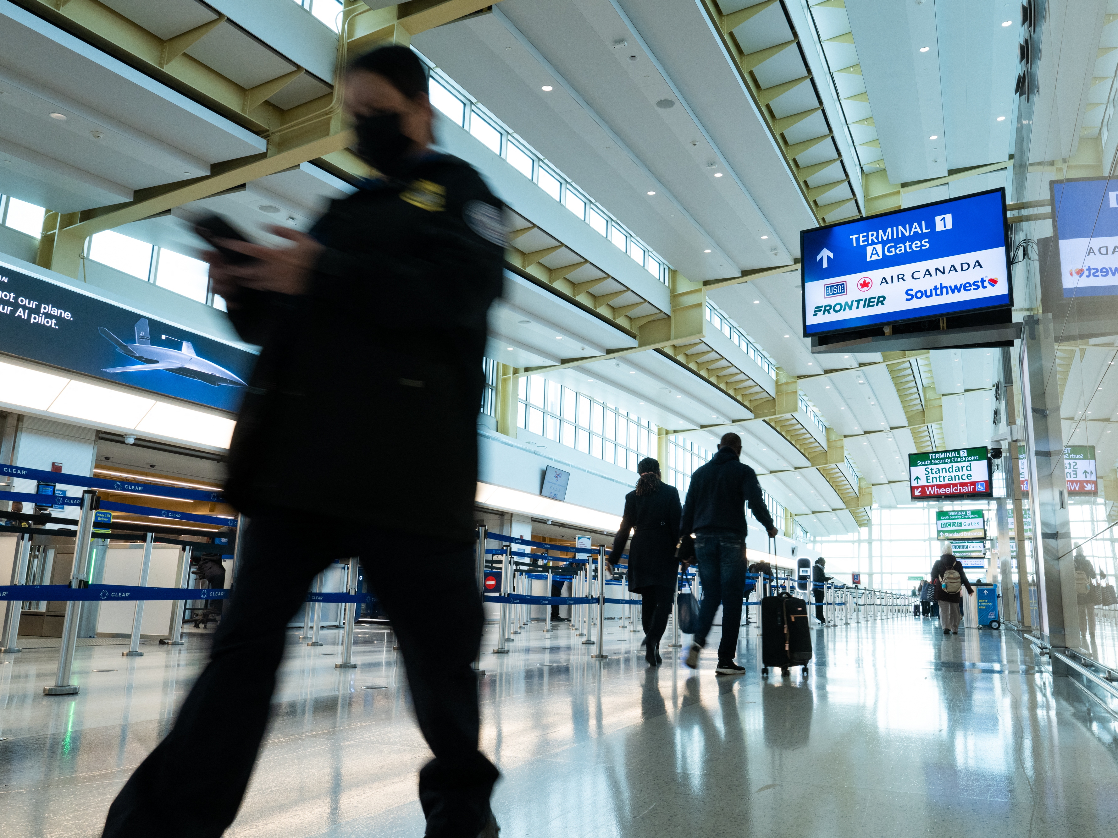 caption: Travelers and staff walk through Ronald Reagan Washington National Airport in Arlington, Va., on Friday. U.S. Transportation Security Administration security officers missed their first full paycheck Friday as a partial funding shutdown of the government approached the one-month mark.