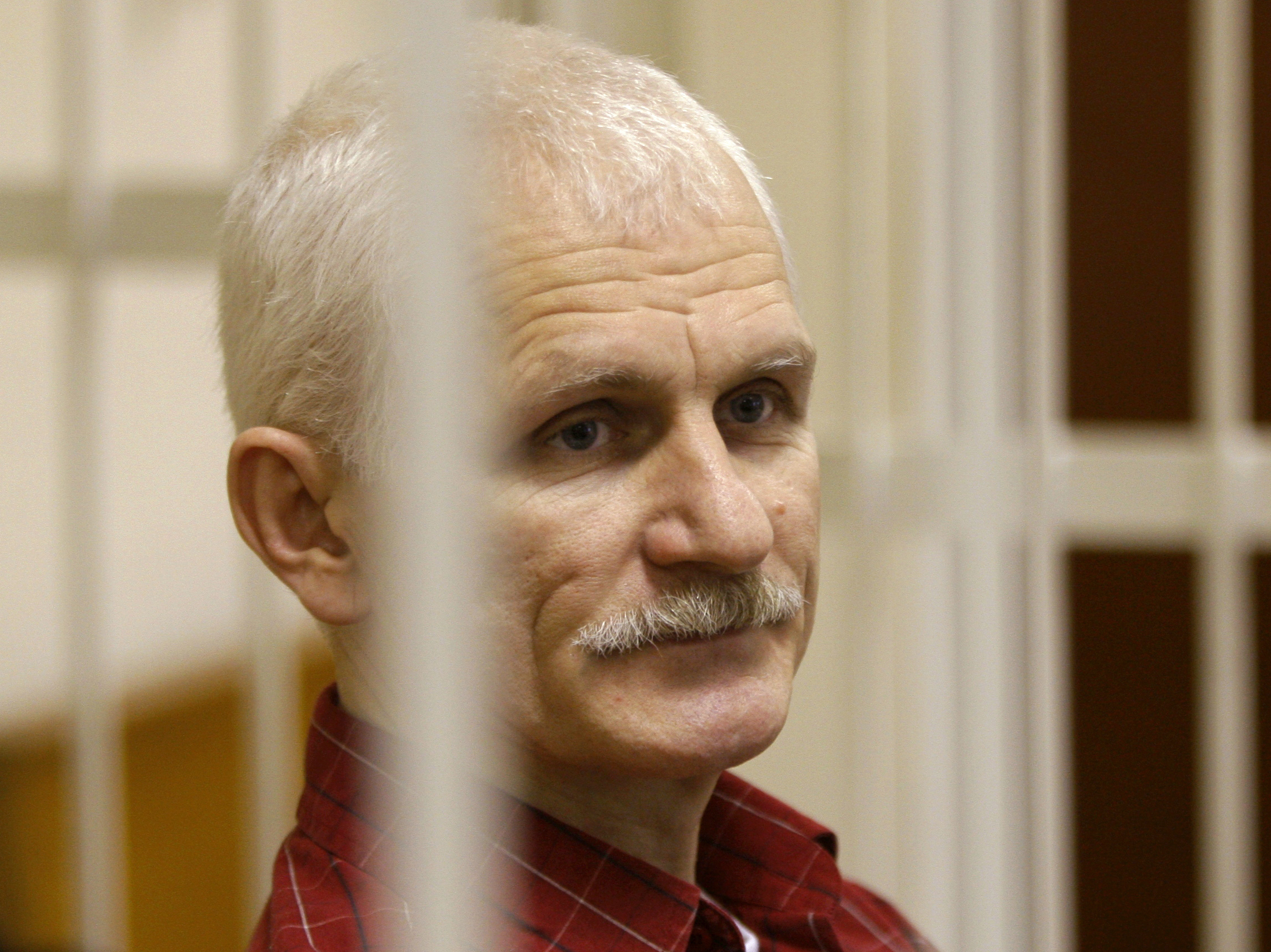 caption: Ales Bialiatski, the head of Belarusian Vyasna rights group, stands in a defendants' cage during a court session in Minsk, Belarus, in 2021.
