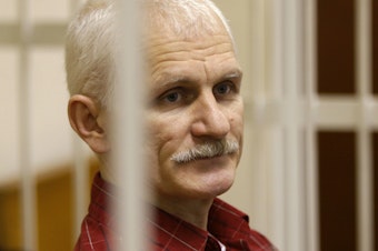 caption: Ales Bialiatski, the head of Belarusian Vyasna rights group, stands in a defendants' cage during a court session in Minsk, Belarus, in 2021.