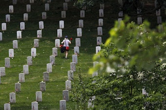 caption: A volunteer places flowers at the base of tombstones during an event at Arlington National Cemetery in in Arlington, Va., ahead of Memorial Day. (Tom Brenner/Getty Images)