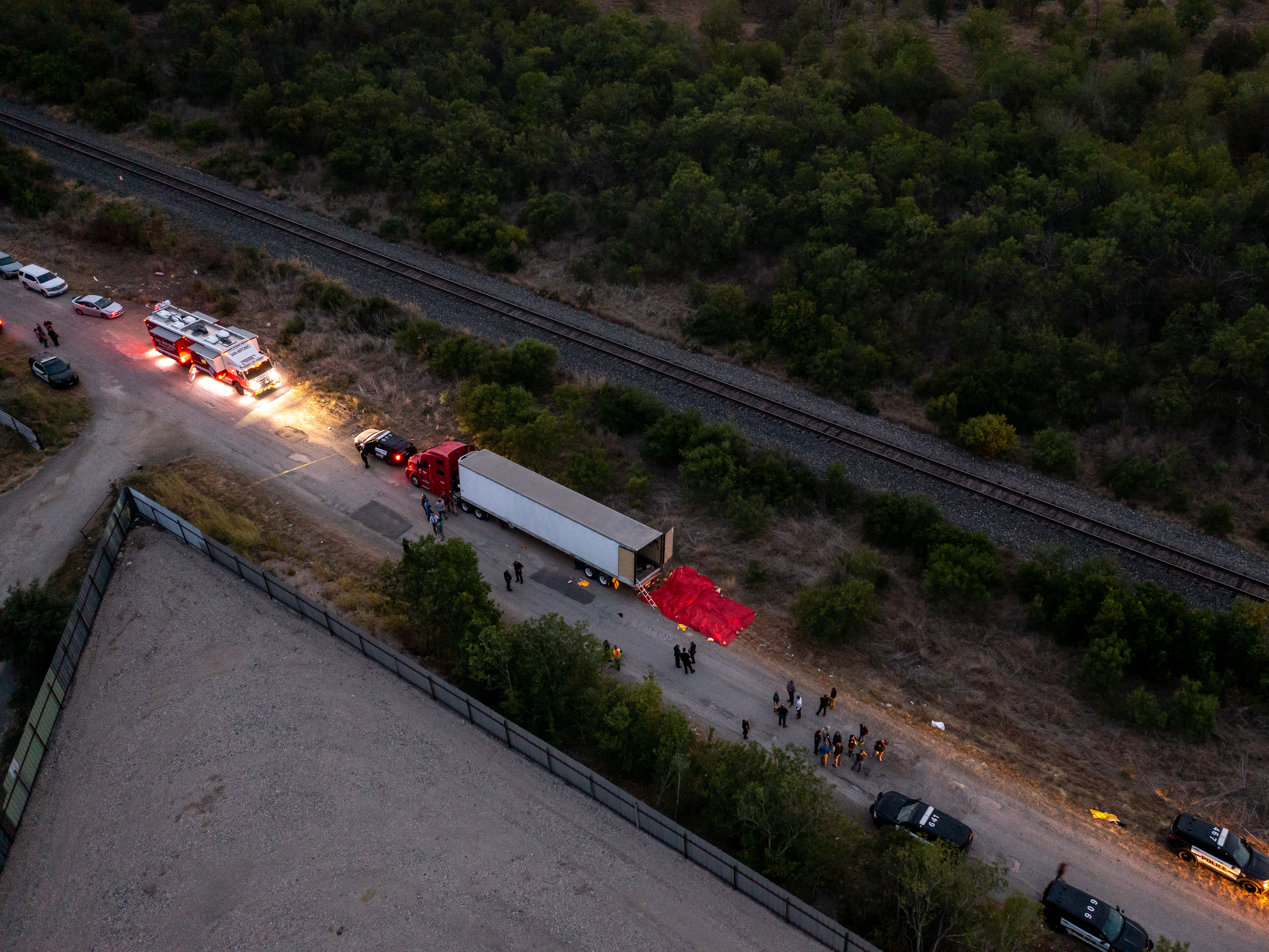 caption: In this aerial view, members of law enforcement investigate a tractor trailer on Monday in San Antonio, Texas.