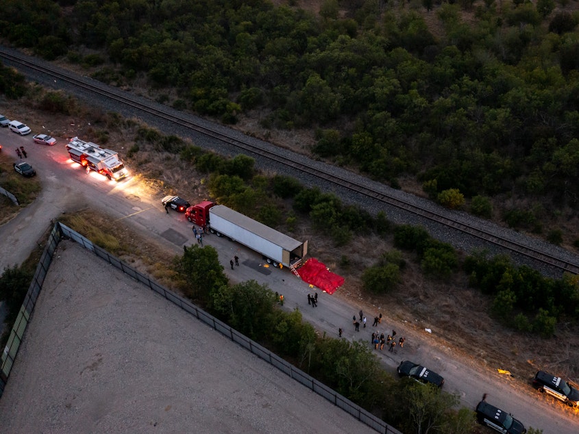 caption: In this aerial view, members of law enforcement investigate a tractor trailer on Monday in San Antonio, Texas.