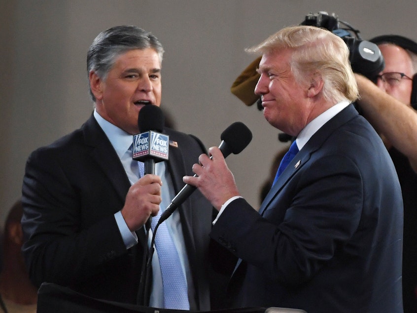 caption: Fox News Channel and other conservative media largely leapt to former President Donald Trump's defense after the FBI searched his Mar-a-Lago resort. Here, Fox star and ally Sean Hannity (L) interviews Trump before a campaign rally in 2018 in Las Vegas.