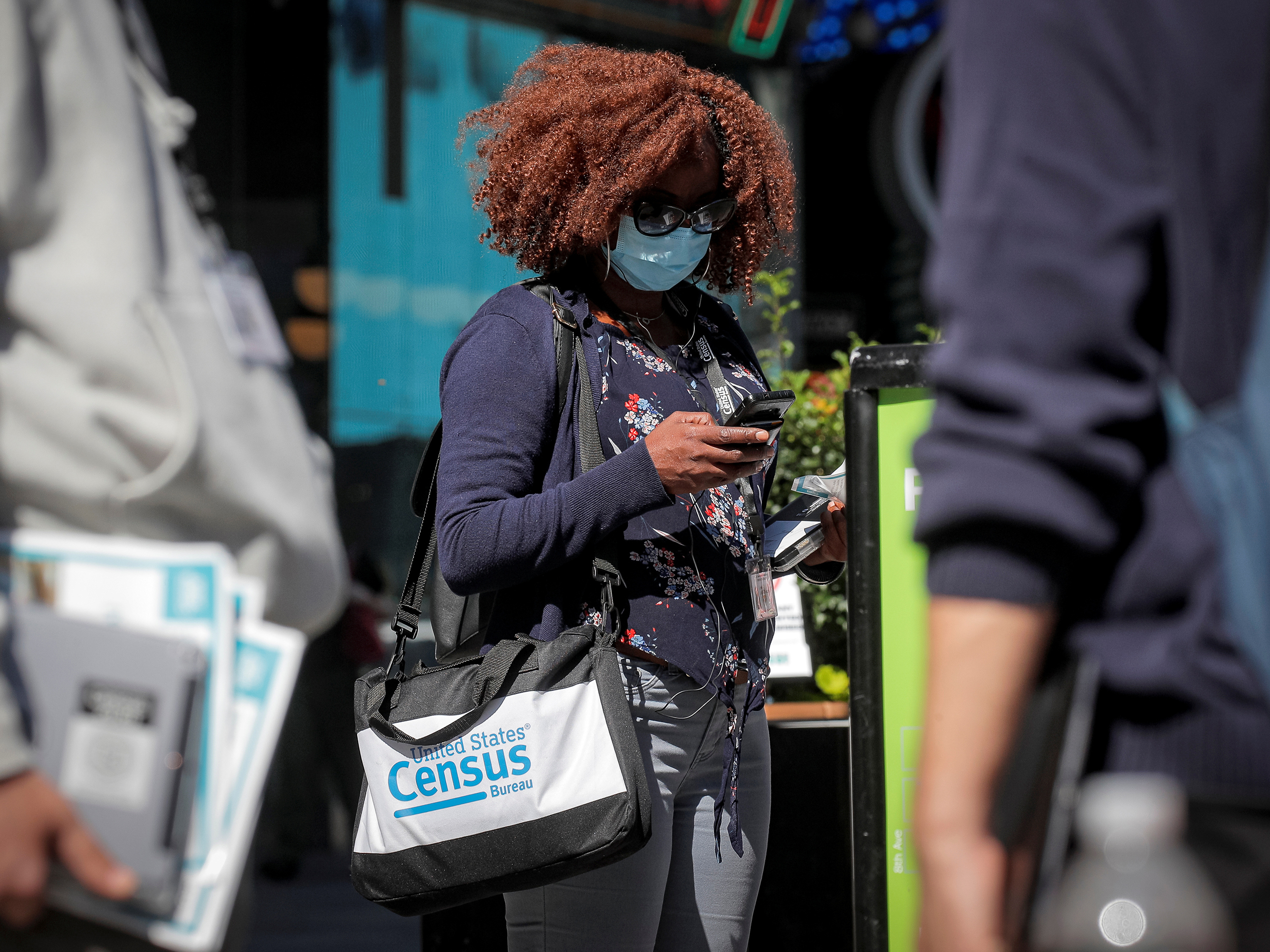 caption: A Census Bureau worker waits to gather information from people during a 2020 census promotional event in New York City.