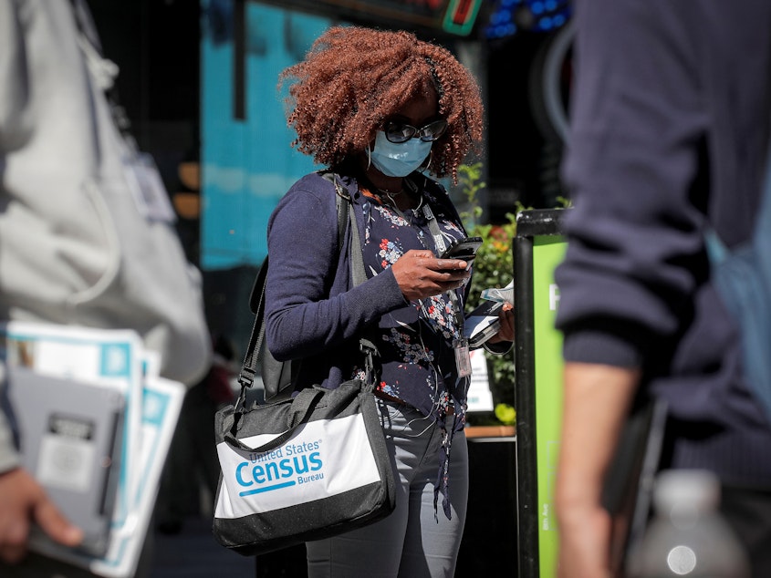 caption: A Census Bureau worker waits to gather information from people during a 2020 census promotional event in New York City.