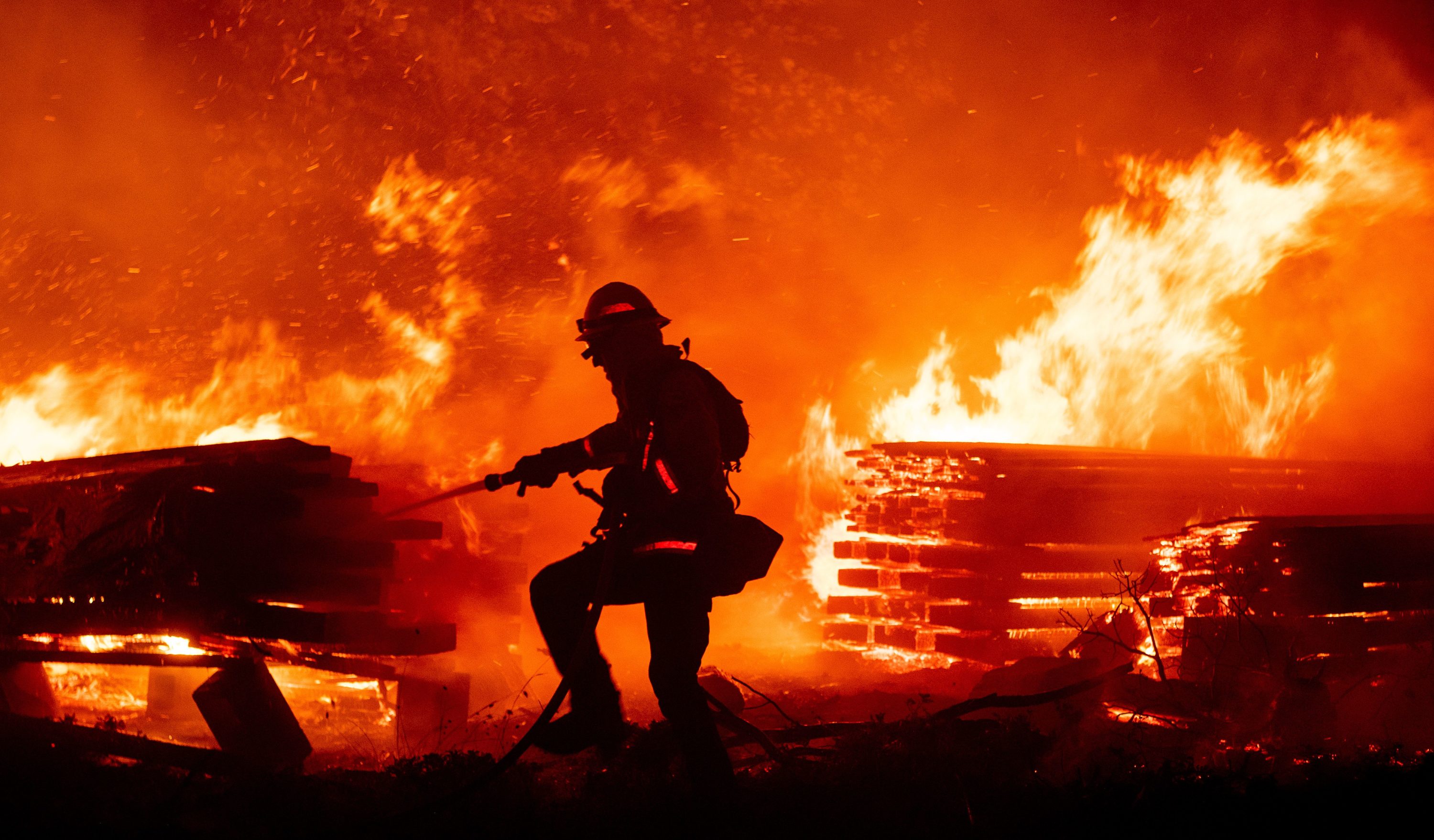 caption: A firefighter douses flames as they push towards homes during the Creek fire in the Cascadel Woods area of unincorporated Madera County, California on September 7, 2020.(JOSH EDELSON/AFP via Getty Images)