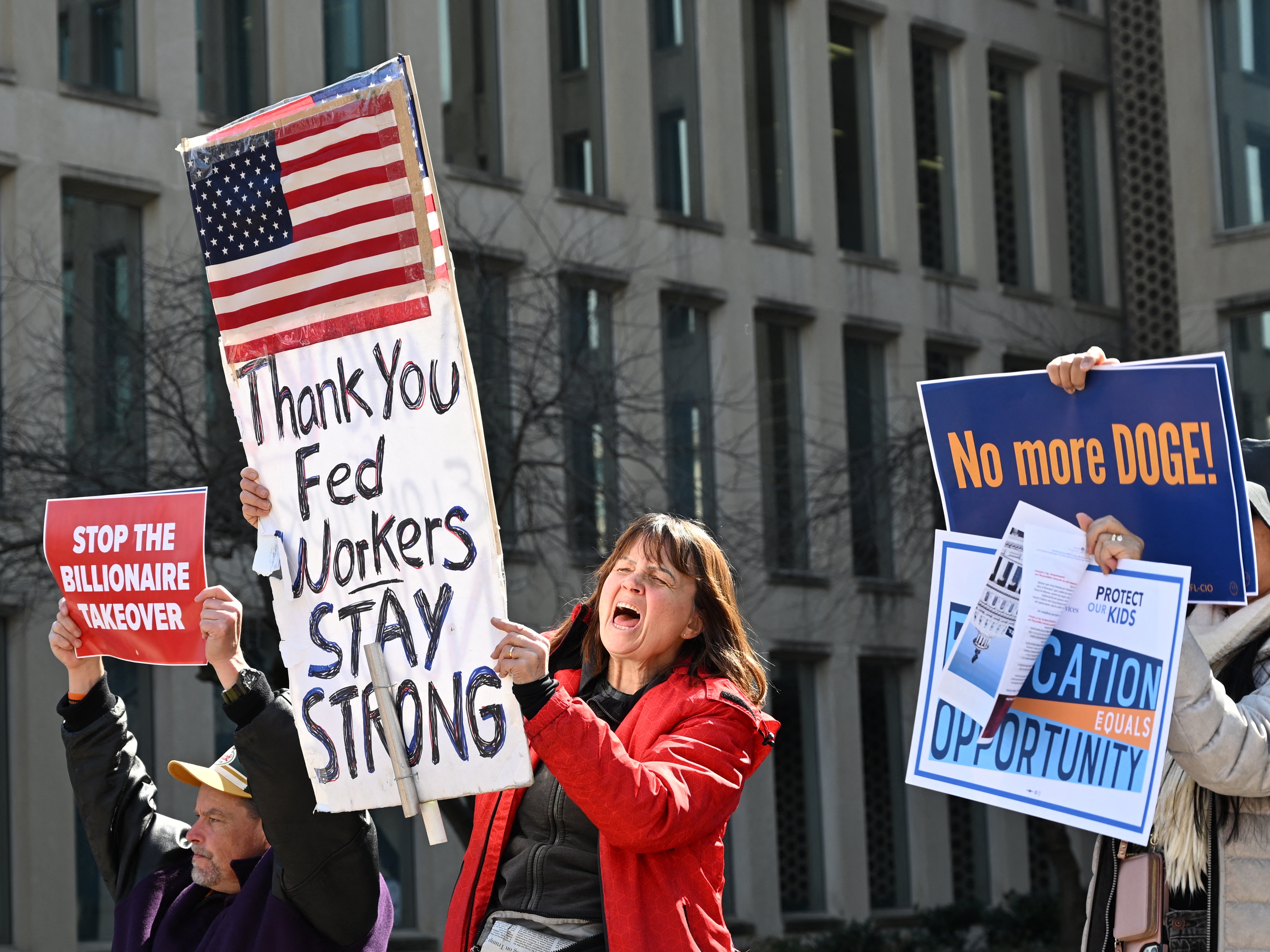 caption: Protesters hold signs in solidarity at a rally in support of federal workers at the Office of Personnel Management in Washington, D.C., on March 4.