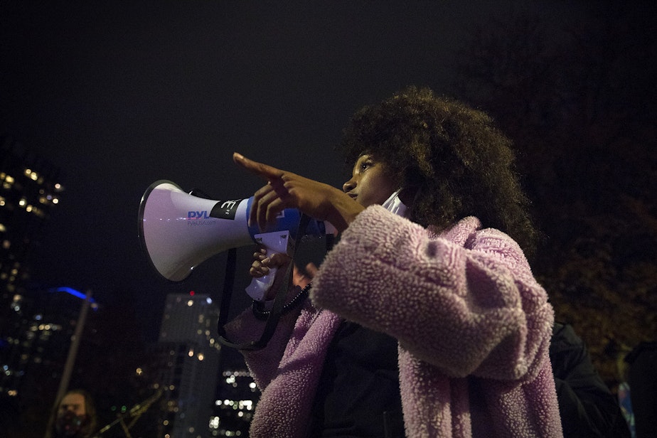 caption: Organizer Katie N. uses a megaphone while speaking to demonstrators on Monday, October 26, 2020, during the 150th day of protests for racial justice in Seattle.