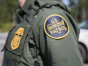 caption: A U.S. Border Patrol agent stands at a highway checkpoint on August 1 in West Enfield, Maine.