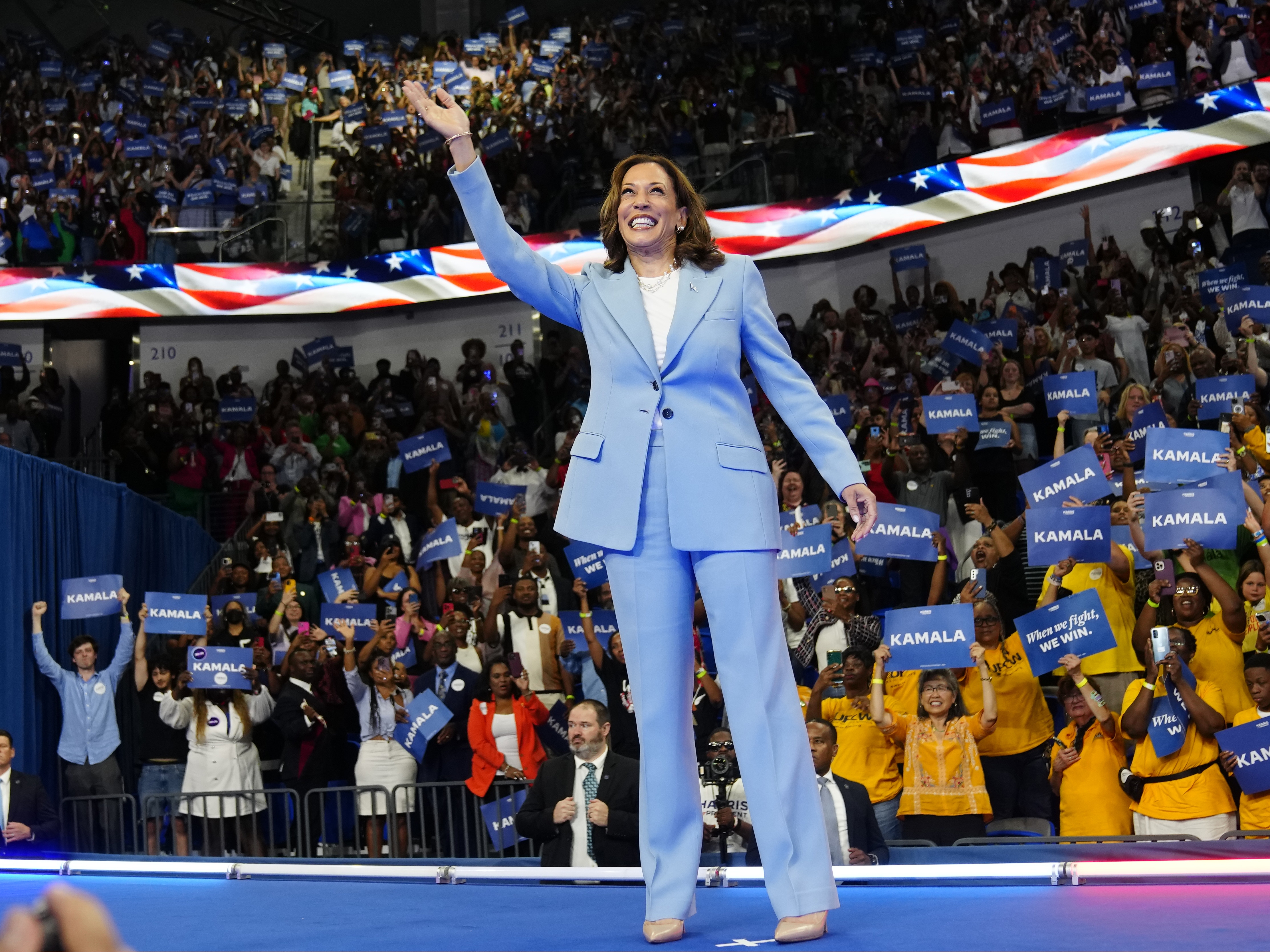 caption: Vice President Harris waves during a packed campaign rally Tuesday in Atlanta.