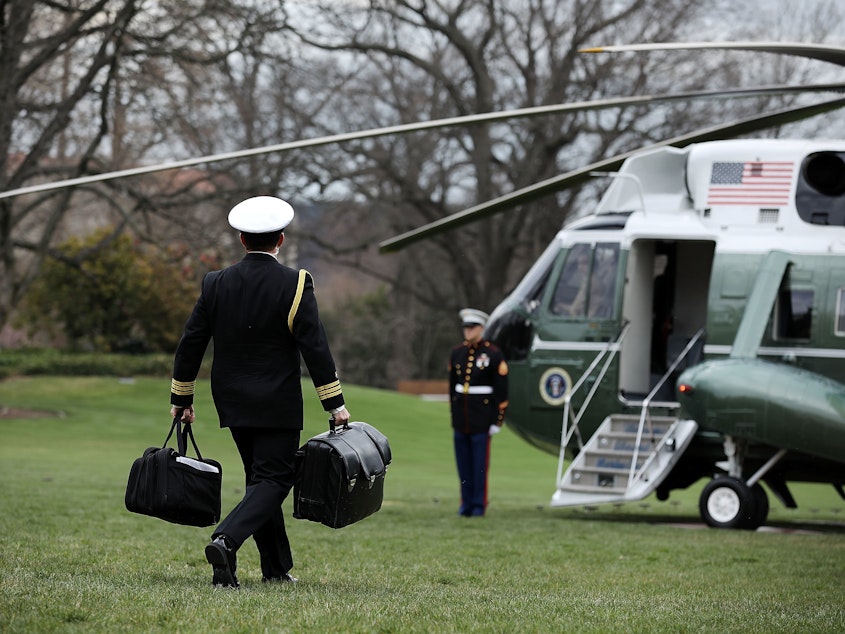 caption: In March 2018, a White House military aide carries the "football," a system that allows President Trump to launch a nuclear strike at any time.